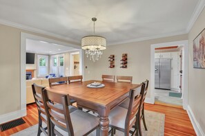 A dining room with a wooden table and chairs, a chandelier, and a wine rack on the wall.