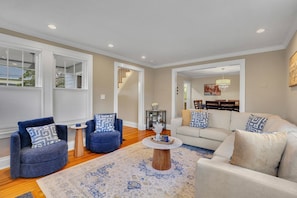 A living room with a sofa, two armchairs, a coffee table, and a rug.