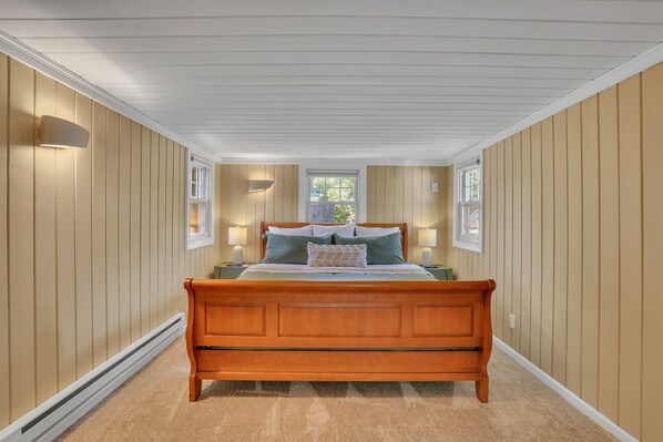 A bedroom with a wooden bed, two bedside tables, and a window.