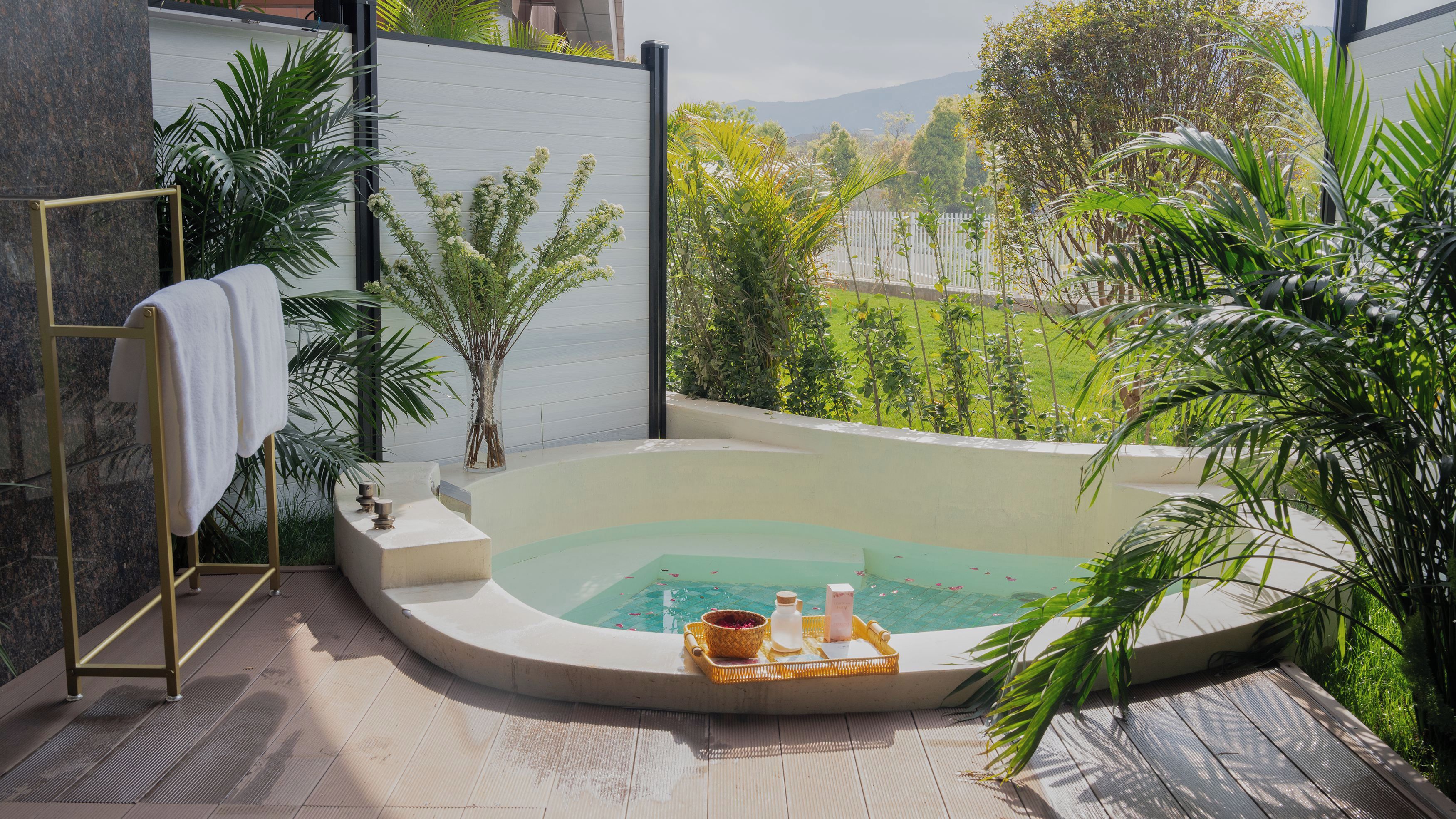A spa area with a hot tub, a towel rack, and a tray with bath products.