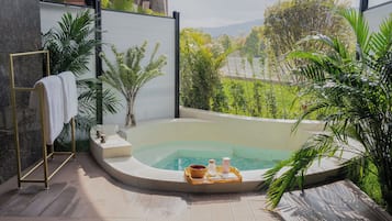A spa area with a hot tub, a towel rack, and a tray with bath products.