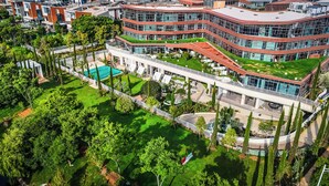 A modern building with multiple levels, a central courtyard with a pool, and surrounding greenery. - SKANDURA GARDEN HOTEL DIANCHI (Kunming)