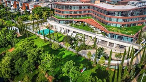 Ein modernes Gebäude mit mehreren Ebenen, einem zentralen Innenhof mit Pool und umliegender Bepflanzung.