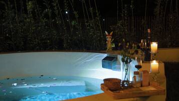 Un área de piscina con una estatua, velas y una mesa con un florero y cristalería.