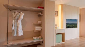 Habitación de hotel con bata y perchero, un estante pequeño con toallas, un refrigerador y vistas al exterior.