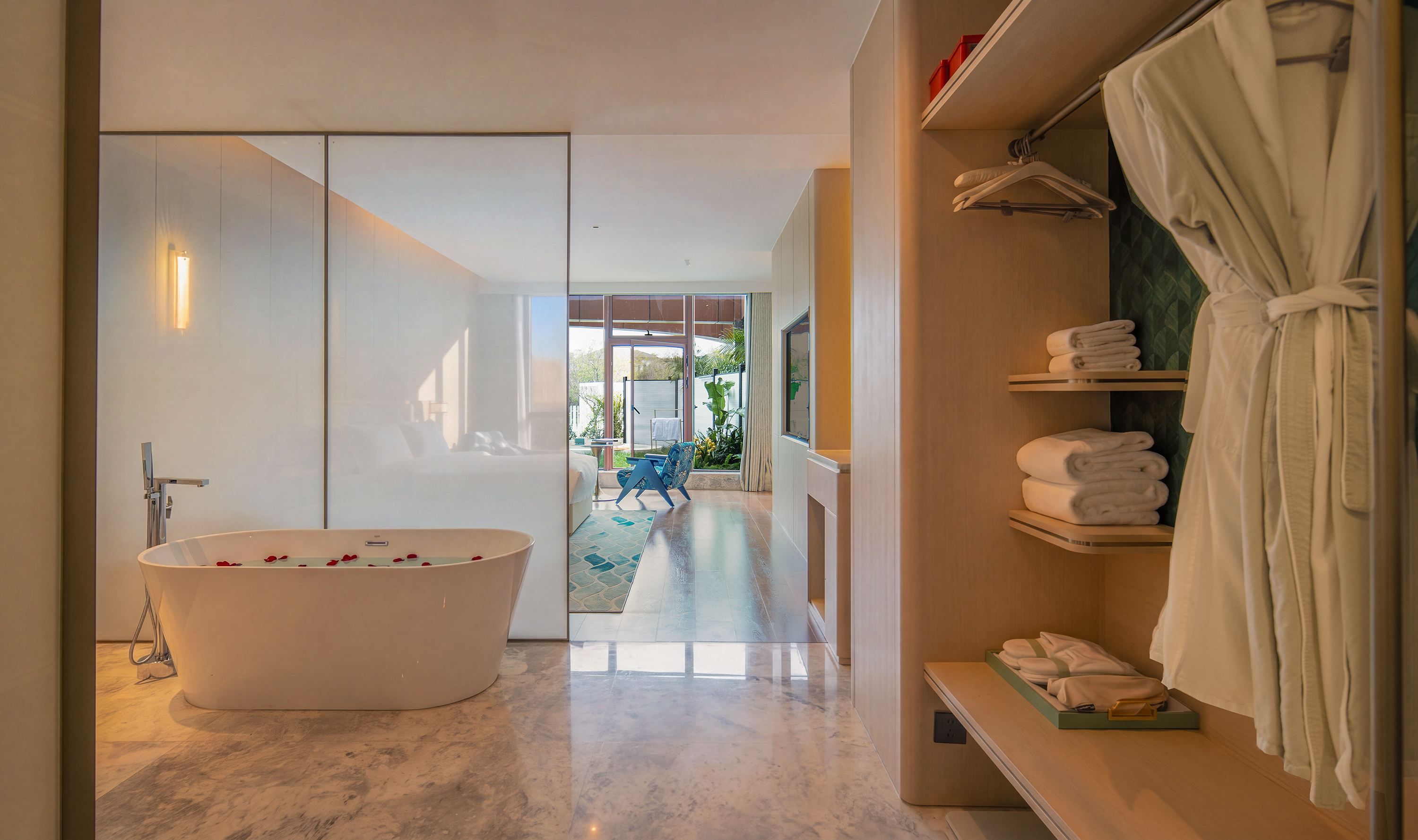 A modern bathroom with a freestanding bathtub, a shower area, and a walk-in closet with neatly folded towels.