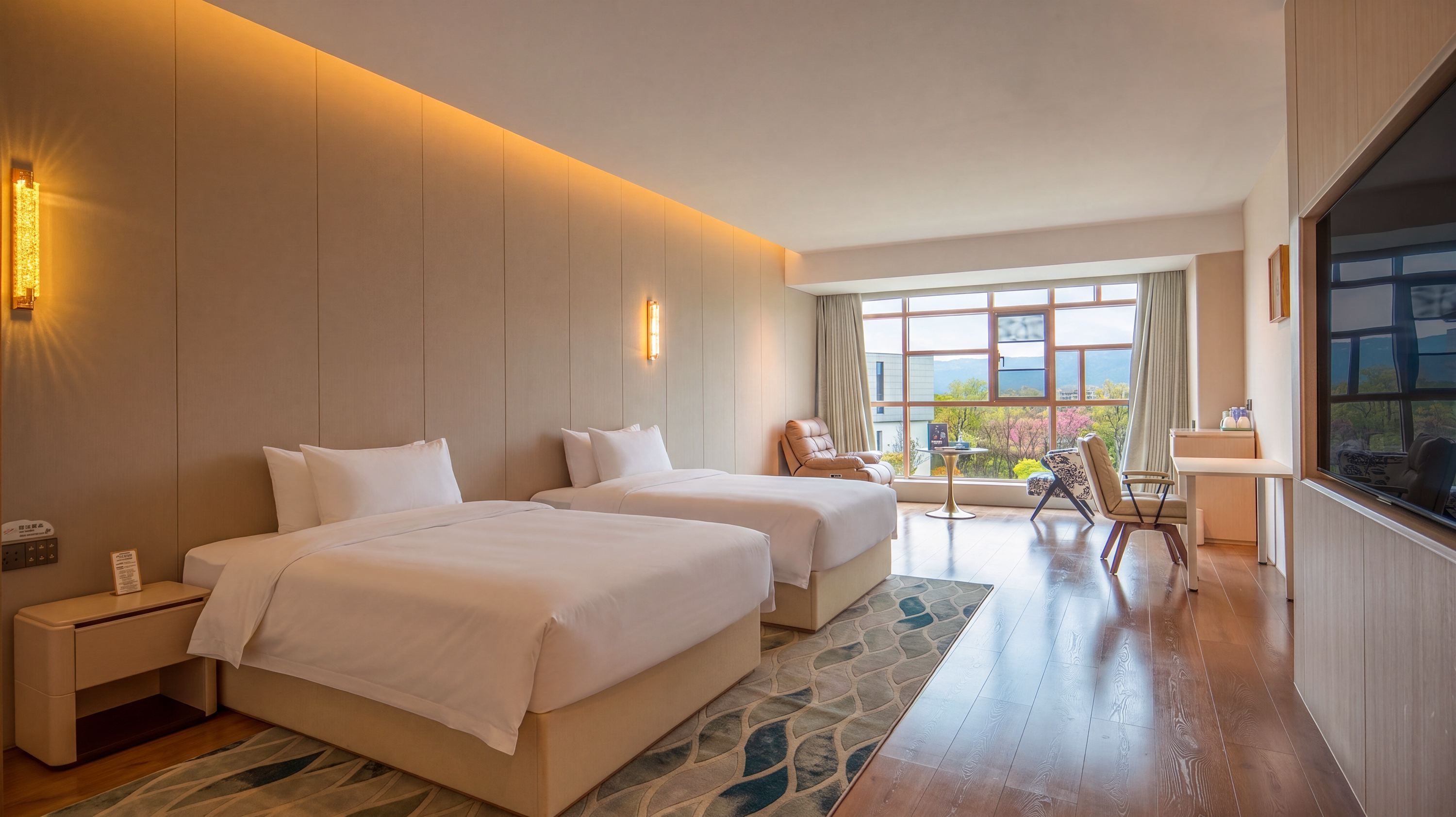 A hotel room with two beds, a seating area, a TV, and a large window offering a view.
