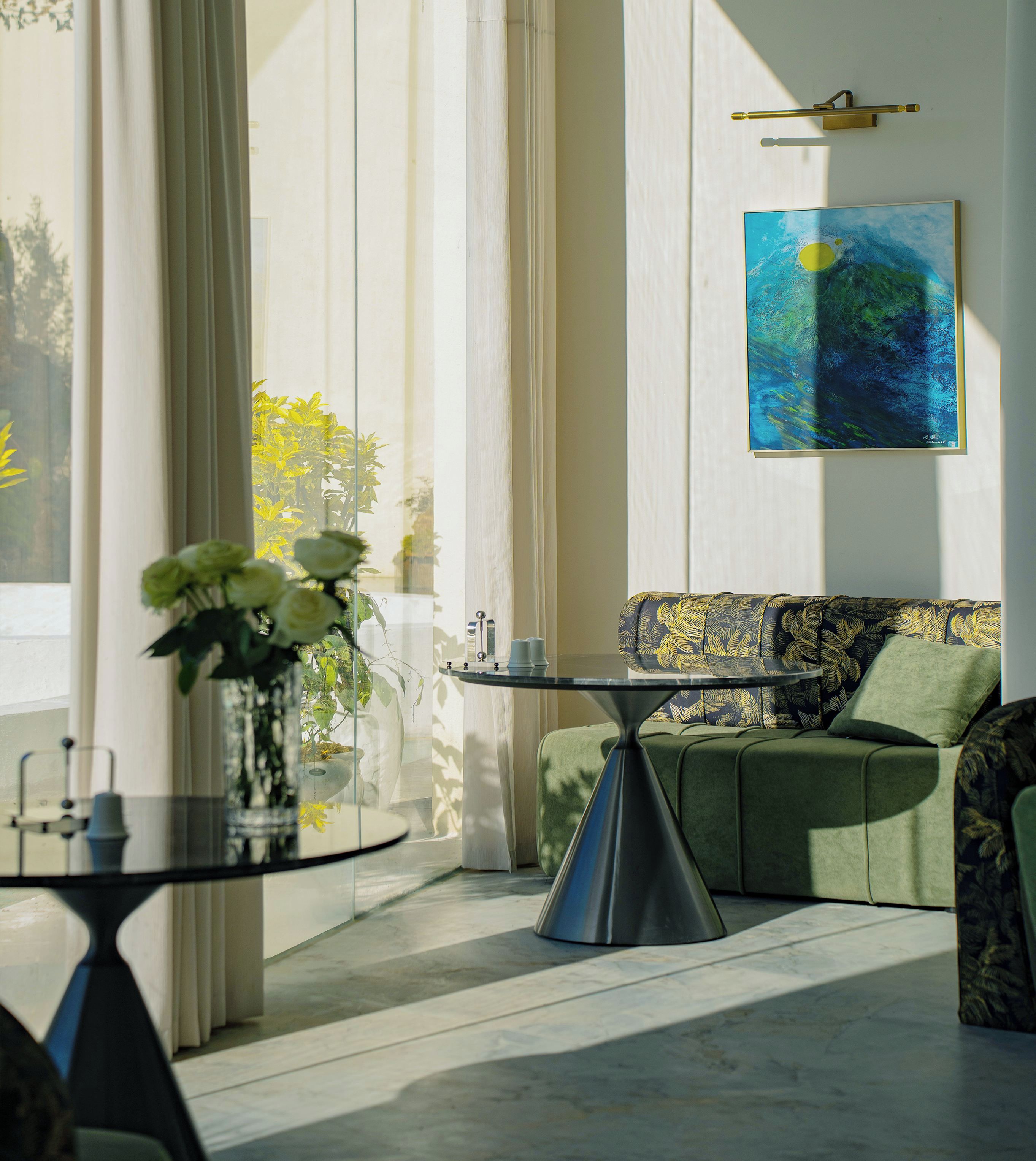 A modern living room with a sofa, a glass coffee table, and a painting on the wall.