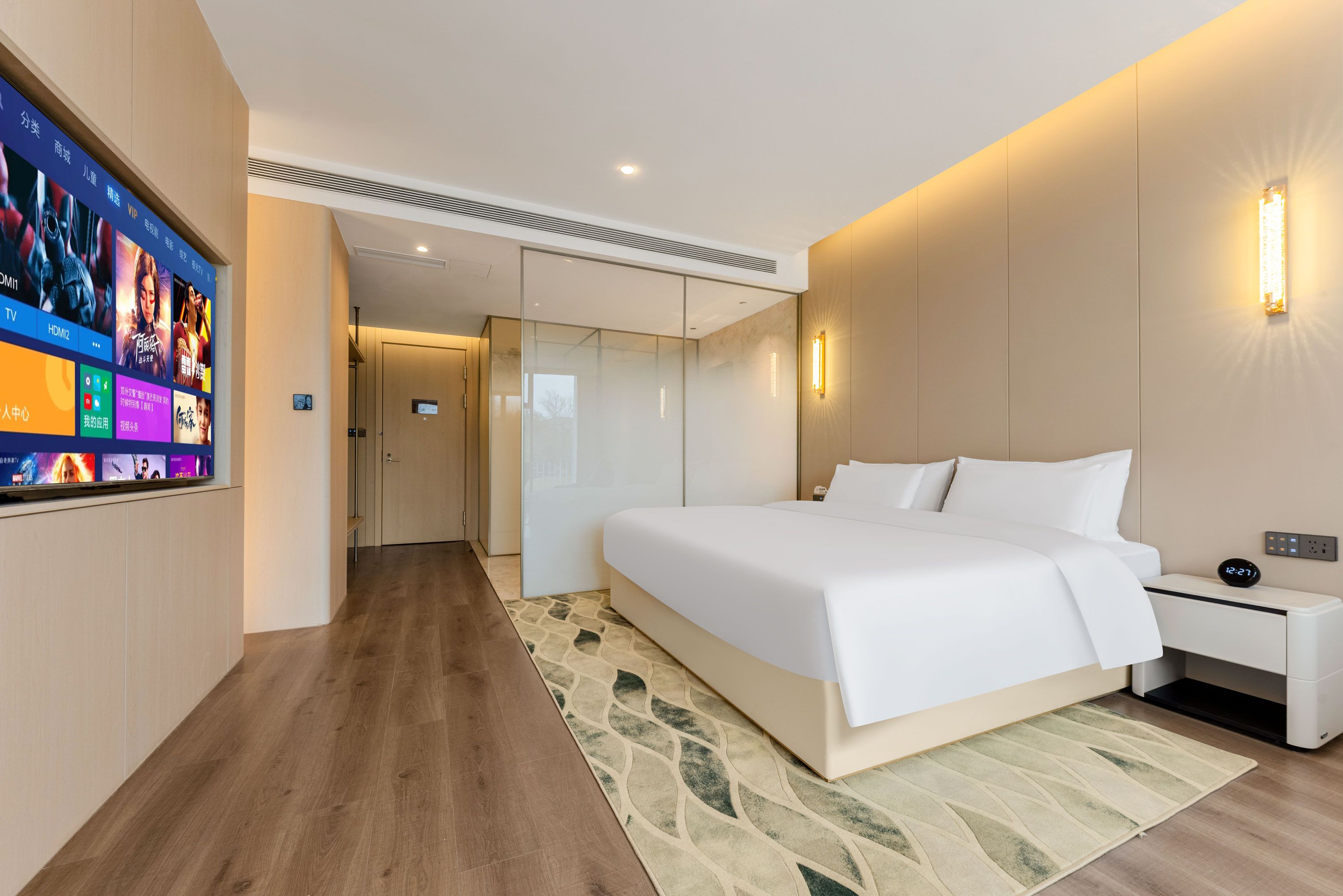 A modern hotel room with a large bed, bedside tables, a TV, and a digital clock.
