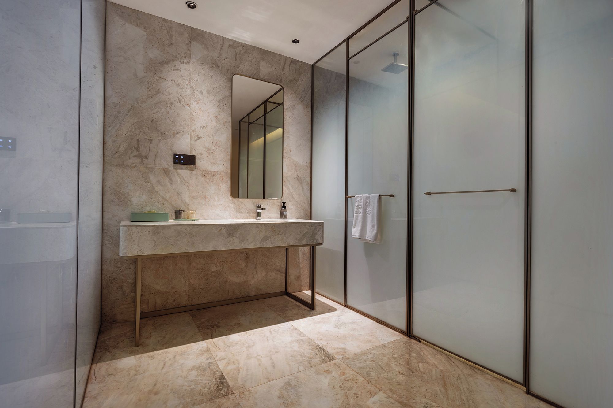 A modern bathroom with a marble countertop, a large mirror, and a glass shower enclosure.