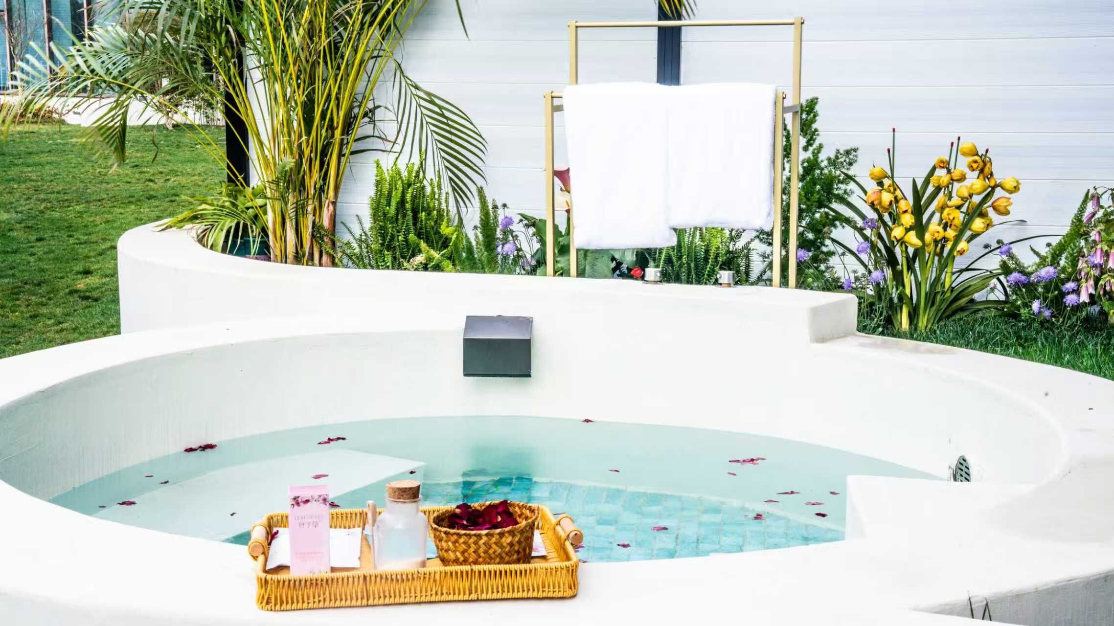 A spa area with a hot tub surrounded by greenery and flowers.