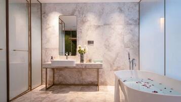 Un baño moderno con una bañera independiente, un espejo grande y un tocador con lavabo.