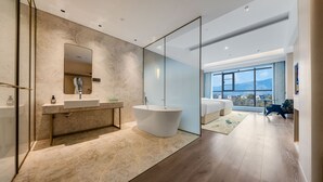 A modern bathroom with a freestanding bathtub, a large mirror, and a vanity with a sink. - SKANDURA GARDEN HOTEL DIANCHI (Kunming)