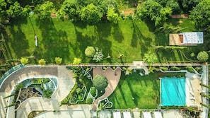 Eine Vogelperspektive eines angelegten Grundstücks mit Schwimmbad, Gartenanlagen und einer überdachten Außenbereich-Sitzgelegenheit.