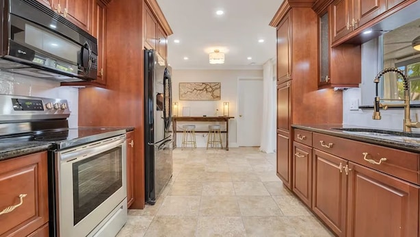 Una cocina con gabinetes de madera, electrodomésticos de acero inoxidable y suelo de baldosas.