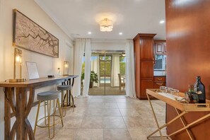 A modern kitchen with a bar area, a dining table with stools, and a view to an outdoor area. - Casa Arkos 3BR Private Pool Beach & Everglades (Coral Springs)