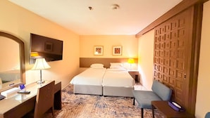 Una habitación de hotel con cama, escritorio, silla y televisor.
