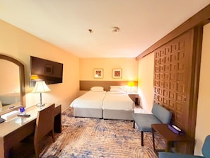 Ein Hotelzimmer mit Bett, Schreibtisch, Stuhl und Fernseher.