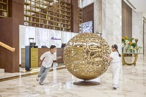 A lobby with a reception desk, a large decorative sphere, and a bookshelf. - Makarem Ajyad Annex (Makkah)