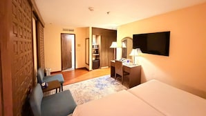 Una habitación de hotel con cama, escritorio, silla, televisor y armario.