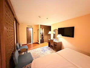 Ein Hotelzimmer mit Bett, Schreibtisch, Stuhl, Fernseher und Kleiderschrank.