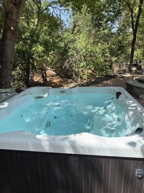 Ein Whirlpool in einem Garten mit Bäumen und einer Steinsitzbank.