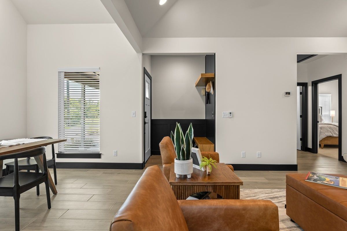A modern living room with a sofa, coffee table, and a dining area with a table and chairs.