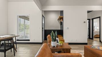 A modern living room with a sofa, coffee table, and a dining area with a table and chairs.