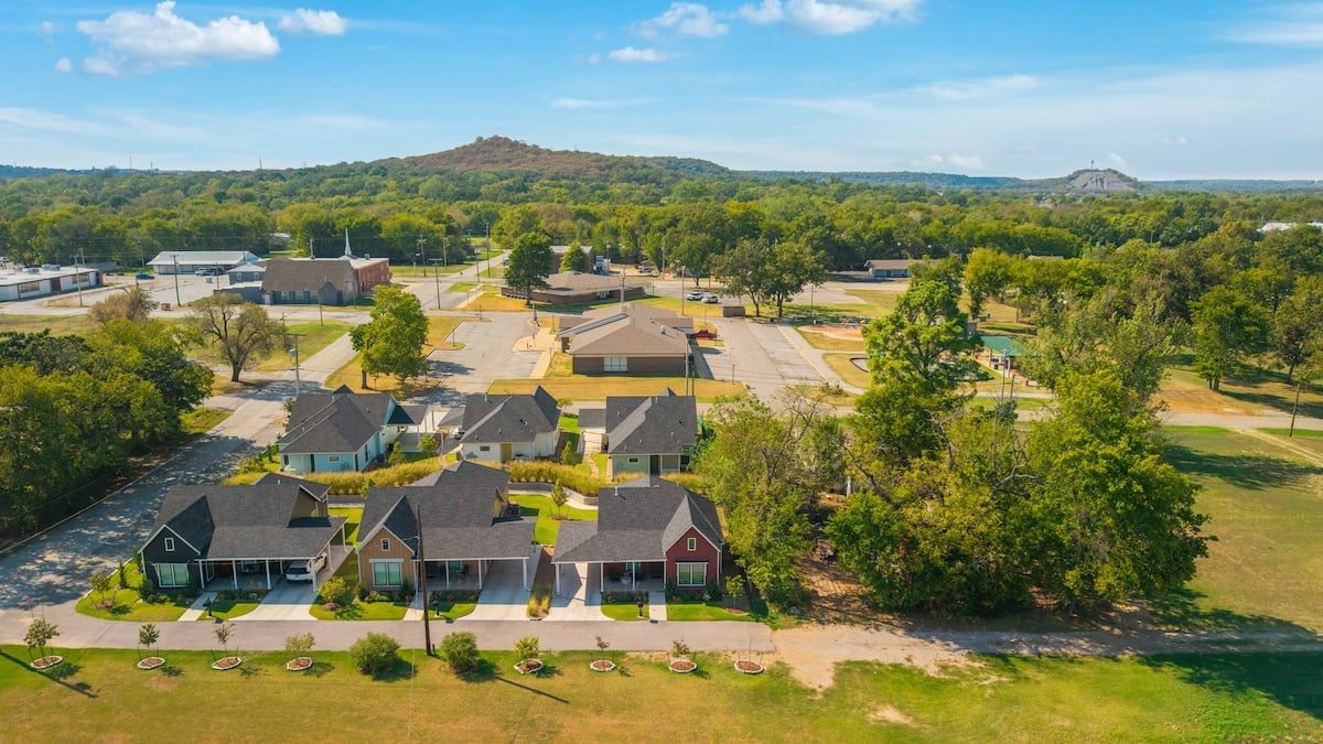 A residential area with houses, a parking lot, and a hill in the background.