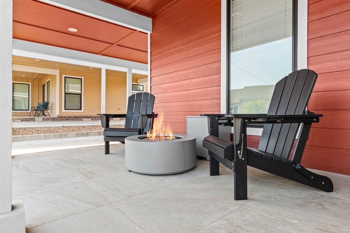 An outdoor seating area with Adirondack chairs and a circular fire pit.