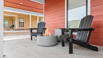 An outdoor seating area with Adirondack chairs and a circular fire pit.