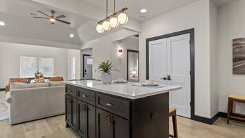 A modern kitchen with a central island, dark cabinetry, and a ceiling fan.