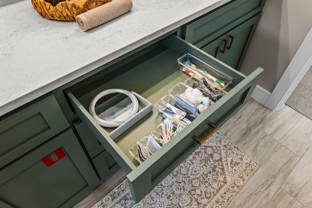 A kitchen with a drawer containing kitchen utensils and a white cable.