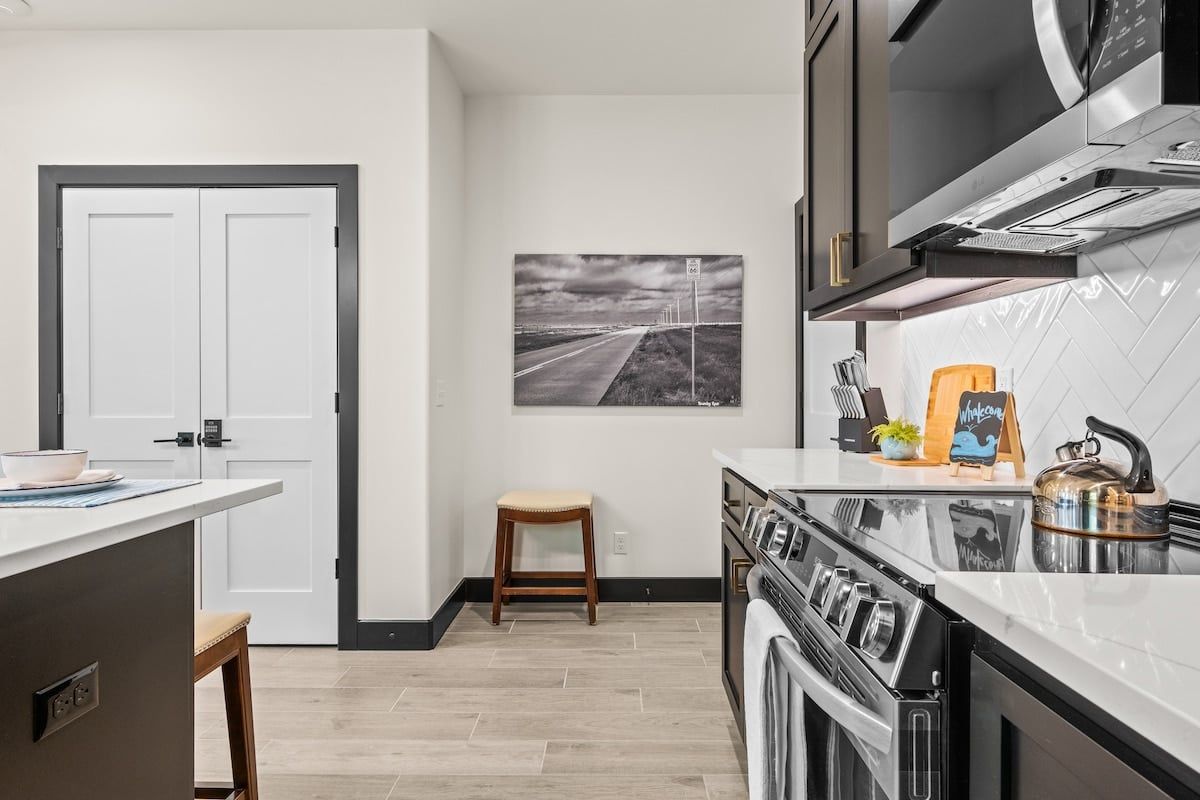 A kitchen with a stove, microwave, and a view of a road through a window.