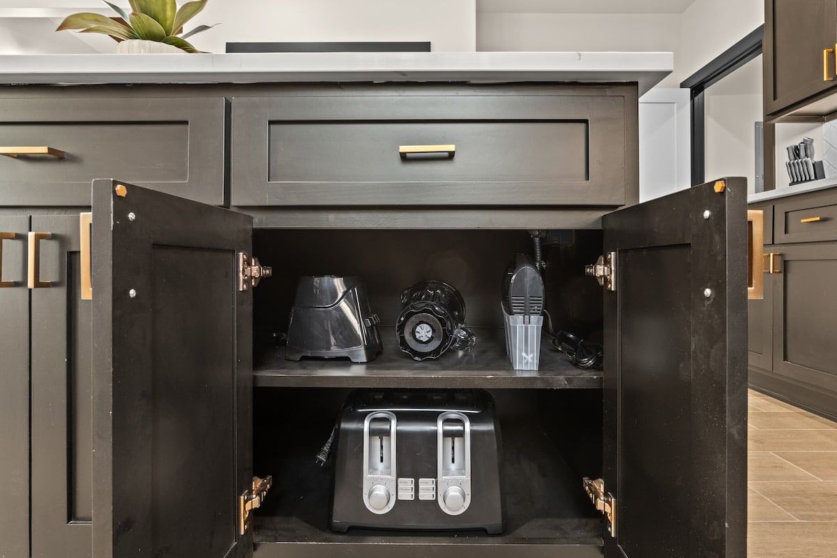 A kitchen with a built-in appliance storage unit containing a toaster, a blender, and a coffee maker.