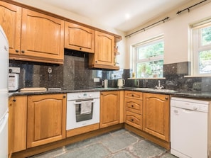 A kitchen with wooden cabinets, a built-in oven, a dishwasher, and a window providing natural light. - Breckon Cottage - dog friendly cottage in Keswick. Sleeps 4 guests (Keswick)