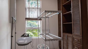 Een kamer met een metalen schap, een stofzuiger en een raam met jaloezieën.