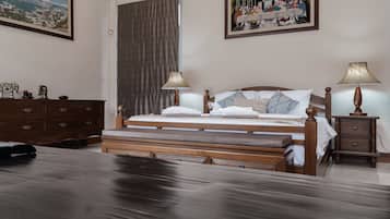 Habitación de hotel con cama de madera, dos lámparas de noche, una mesita de noche, un aparador y dos cuadros en la pared.