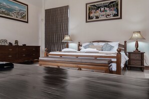 A hotel room with a wooden bed, two bedside lamps, a nightstand, a dresser, and two framed pictures on the wall.