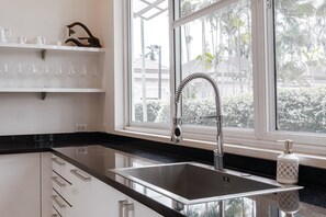 A modern kitchen with a stainless steel sink, black countertop, and white cabinetry.