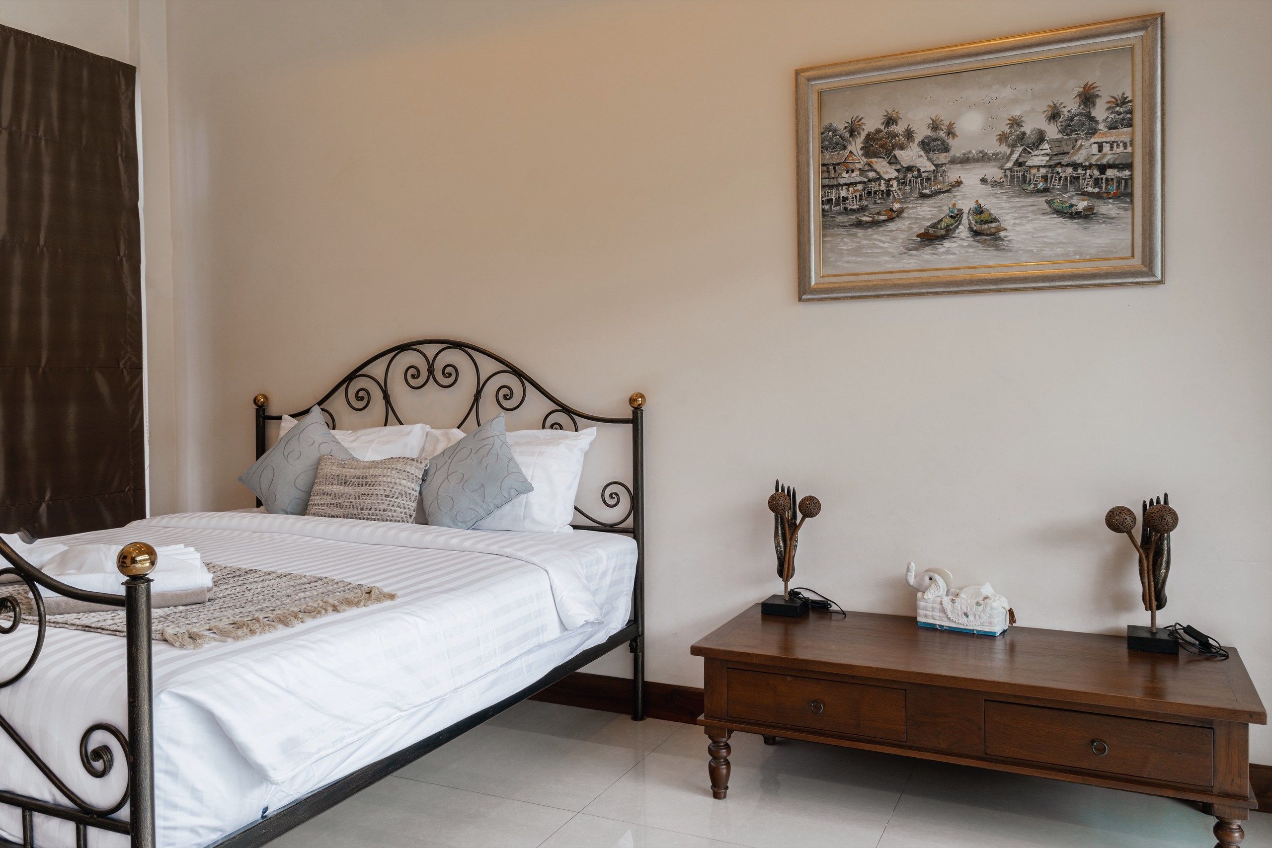 A neatly made bed with a metal frame and a wooden nightstand beside it.