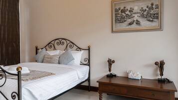 A neatly made bed with a metal frame and a wooden nightstand beside it.