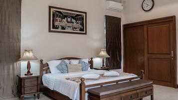 A bedroom with a wooden bed, two bedside tables with lamps, a large wooden wardrobe, and a painting on the wall.