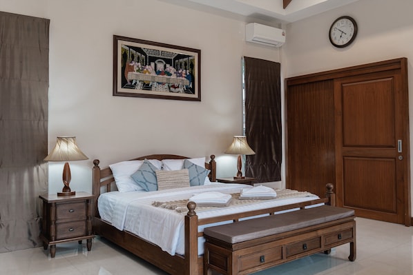 A bedroom with a wooden bed, two bedside tables with lamps, a large wooden wardrobe, and a painting on the wall.