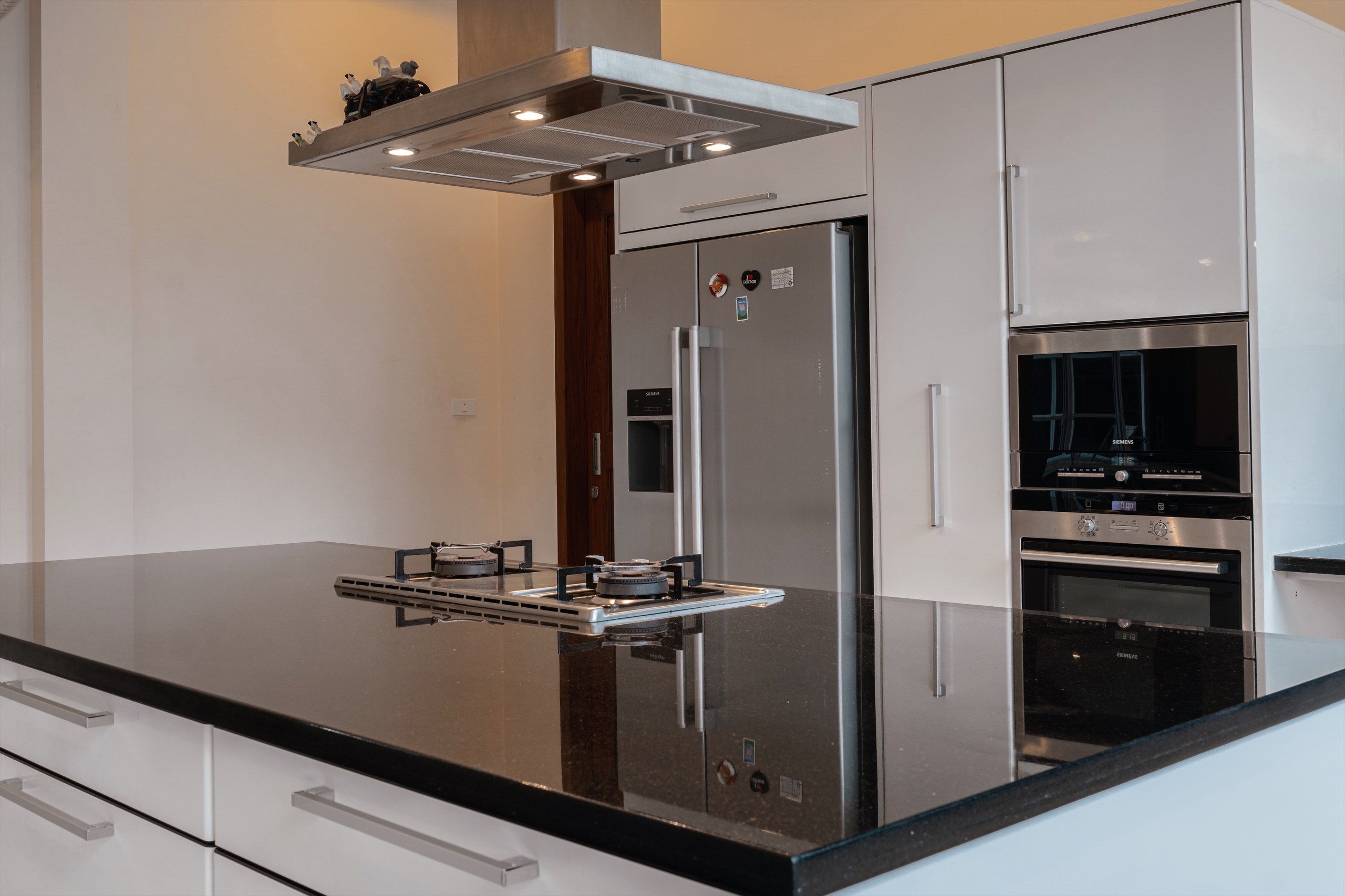 Una cocina moderna con refrigerador de acero inoxidable, horno doble y estufa a gas.