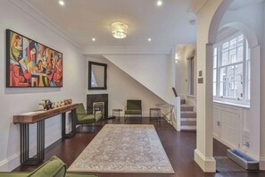 A spacious living room with a fireplace, a green armchair, a coffee table, and a large abstract painting on the wall. - Elvaston Mews

Peaceful 3-bedroom townhome in charming London neighborhood (London)