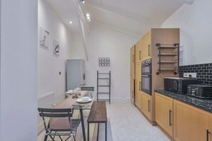 A compact kitchen with a dining area, featuring a built-in oven, a coffee machine, and a wall-mounted rack. - Elvaston Mews

Peaceful 3-bedroom townhome in charming London neighborhood (London)
