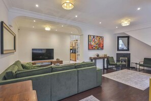 A modern living room with a sectional sofa, a flat-screen TV, a fireplace, and a dining area with a table and chairs. - Elvaston Mews

Peaceful 3-bedroom townhome in charming London neighborhood (London)