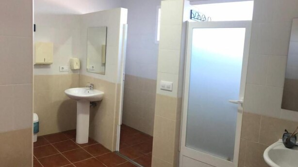Casa de banho com lavatório, espelho e chuveiro.