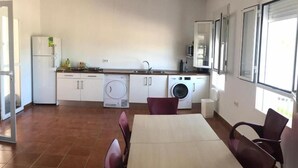 Cozinha compacta com área de jantar, máquina de lavar e geladeira.